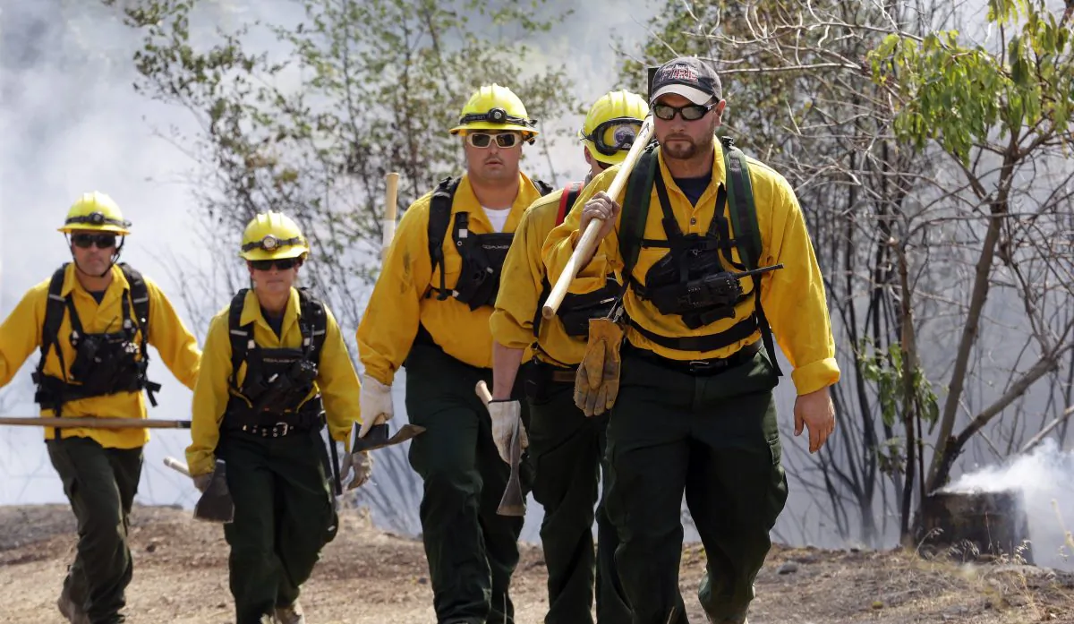 A group of firefighters head up a hill to keep an eye on an area burning between houses and the main fire on Aug. 22, 2015 in Okanogan, Wash. (AP Photo/Elaine Thompson)