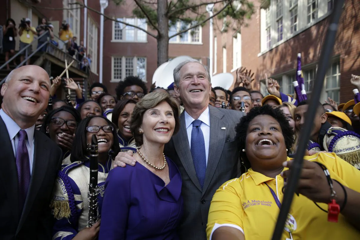 Former President George W. Bush poses for a 'selfie' photo with former first lady Laura Bush, marching band director Asia Muhaimin, right, and New Orleans Mayor Mitch Landrieu, far left, at Warren Easton Charter High School in New Orleans, Friday, Aug. 28, 2015. Bush is in town to commemorate the 10th anniversary of Hurricane Katrina, which is Saturday. (AP Photo/Gerald Herbert)