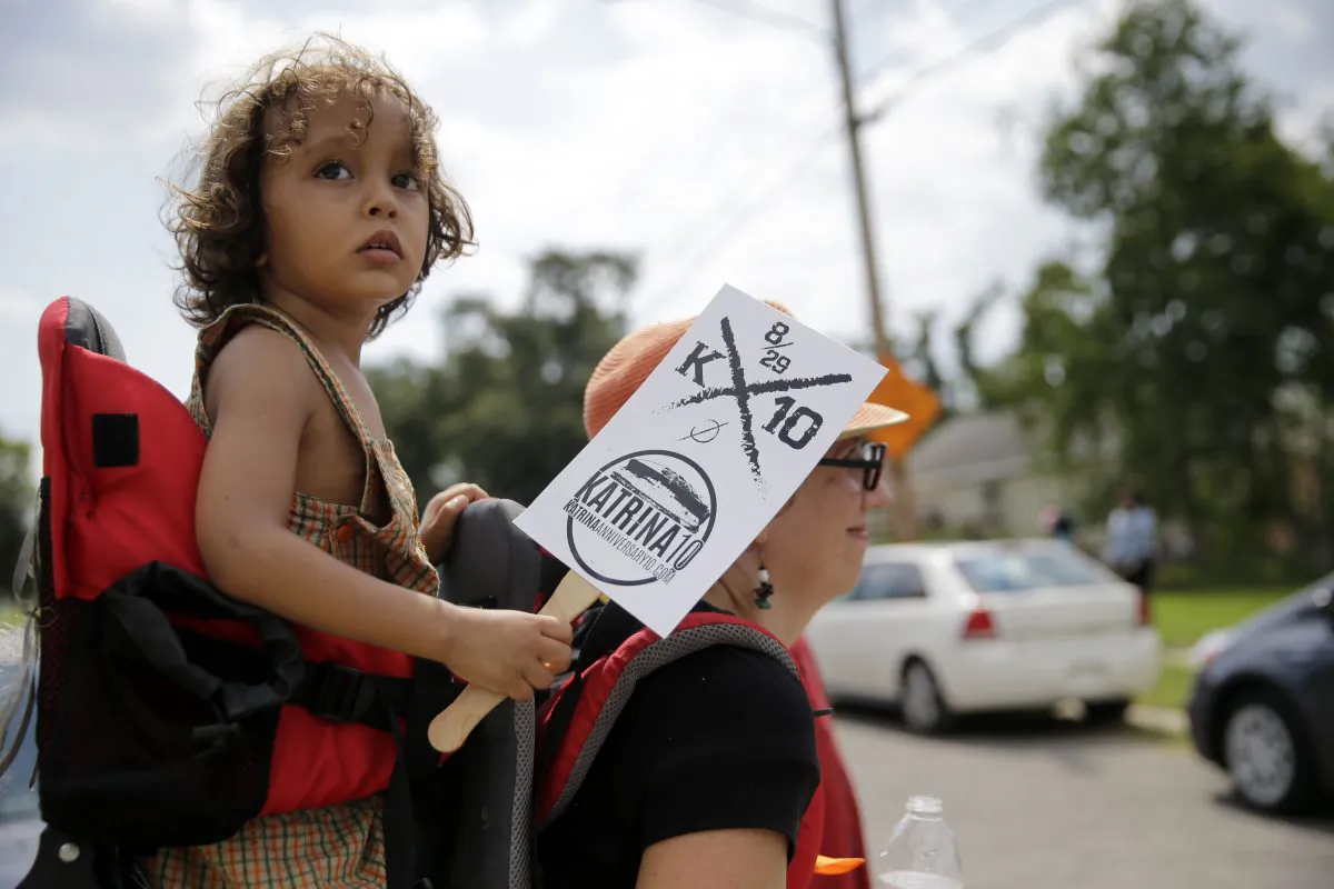 Rizzo Santana, 2, walks with his mother Sierra Santana during a second-line parade to commemorate the 10th anniversary of Hurricane Katrina in the Lower 9th Ward of New Orleans, Saturday, Aug. 29, 2015. (AP Photo/Gerald Herbert)