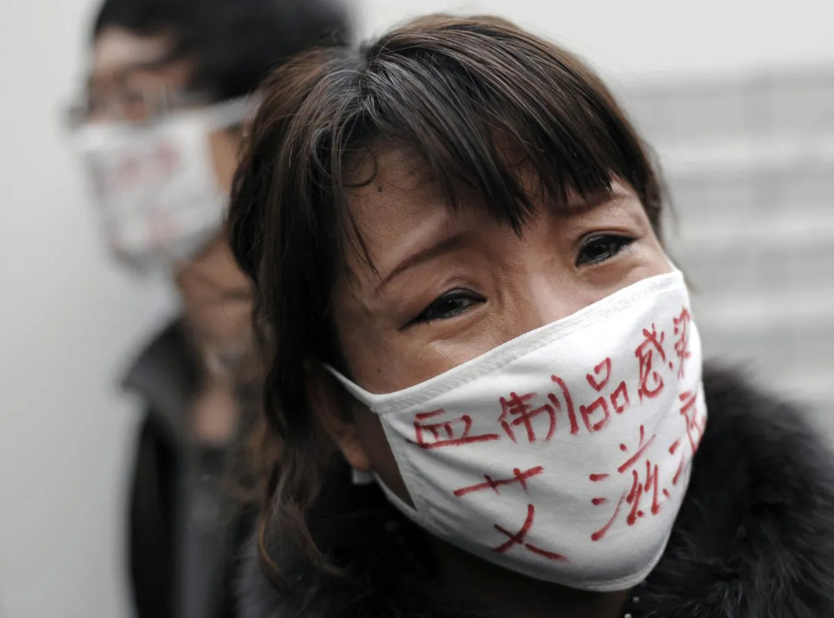 A woman, whose son was infected with HIV, wears a face mask bearing the words "Blood products infect us with AIDS," as she cries during an AIDS awareness event on the World AIDS Day held at Beijing's south railway station on Dec. 1, 2009. (Andy Wong/AP Photo)
