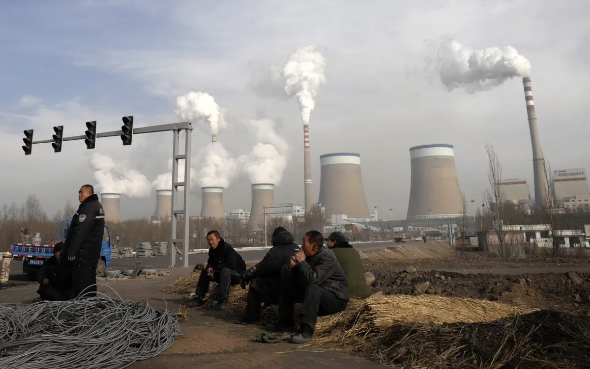 Chinese workers take a break in front of the cooling towers of a coal-fired power plant in Dadong, Shanxi province, China, on Dec. 3, 2009. (AP Photo/Andy Wong, File)