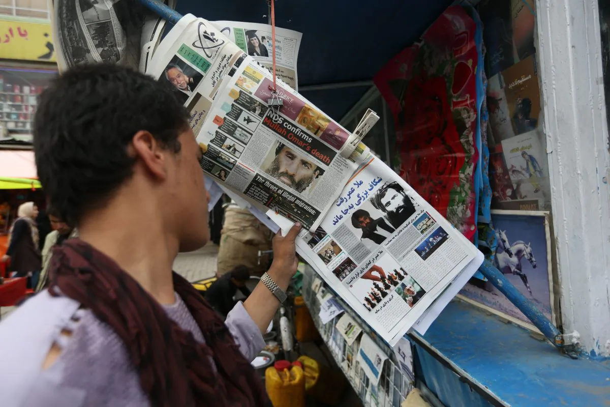 In this Saturday, Aug. 1, 2015, photo, An Afghan boy reads a local newspaper at a news stand carrying a headline about the new leader of the Afghan Taliban, Mullah Akhtar Mohammad Mansoor, in Kabul, Afghanistan. (AP Photo/Rahmat Gul)