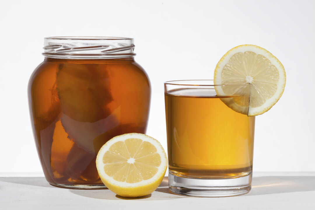 Kombucha superfood pro biotic beverage in glass with lemon on white back