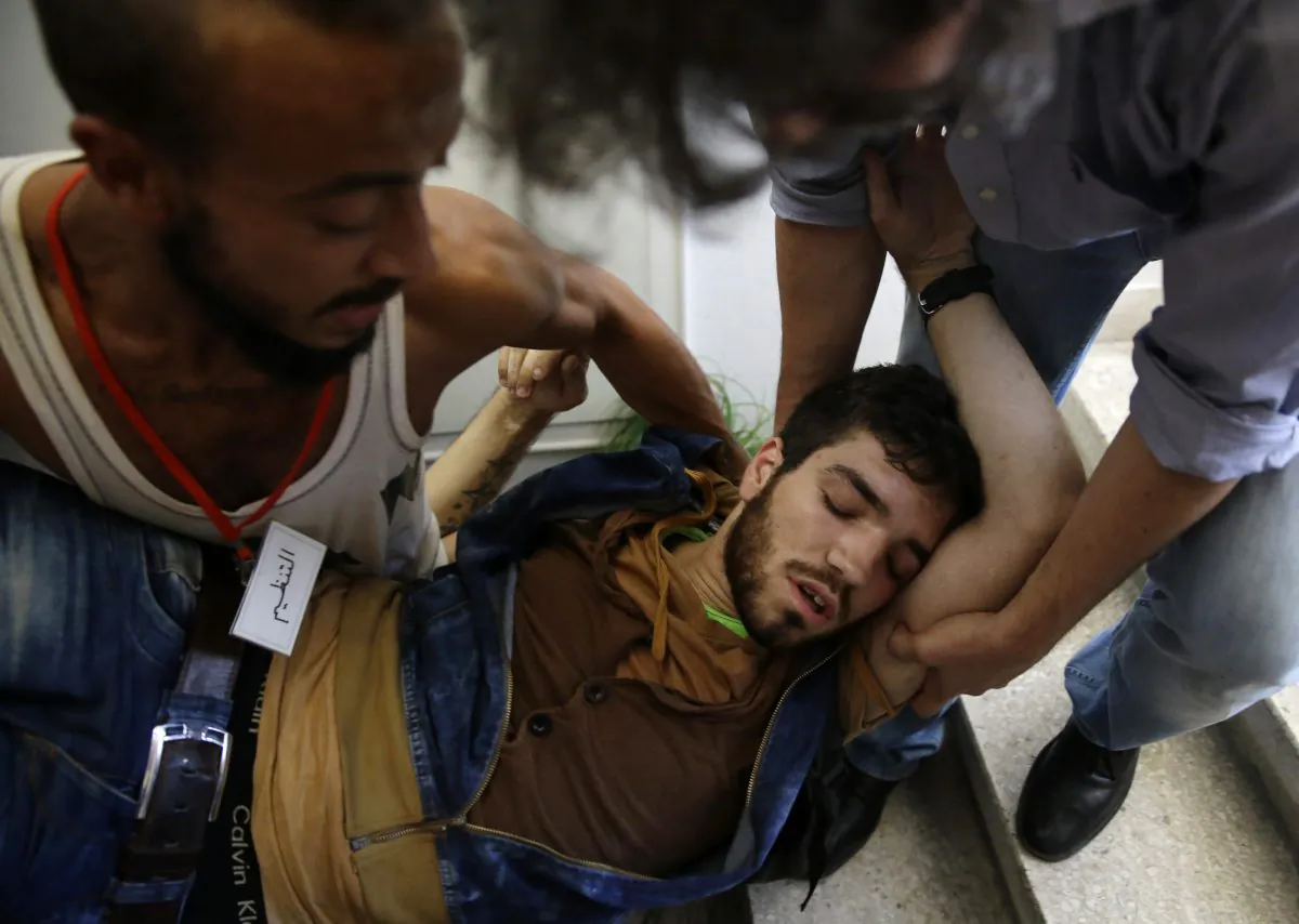 A Lebanese activist is assisted after Lebanese security forces dragged a number of activists out of the Environment Ministry in downtown Beirut, Lebanon, Tuesday, Sept. 1, 2015. Lebanese security forces dragged a number of activists out of the Environment Ministry in downtown Beirut, where they were staging an hour-long sit-in on Tuesday demanding the minister's resignation over a trash crisis that has ignited mass protests. (AP Photo/Hassan Ammar)