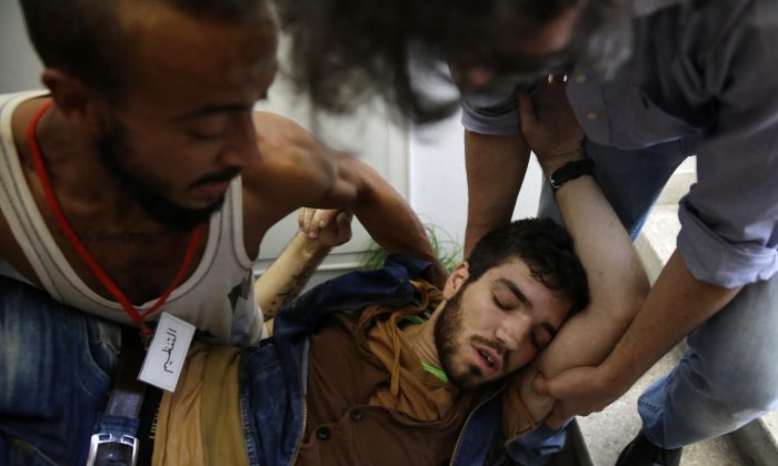 A Lebanese activist is assisted after Lebanese security forces dragged a number of activists out of the Environment Ministry in downtown Beirut, Lebanon, Tuesday, Sept. 1, 2015. Lebanese security forces dragged a number of activists out of the Environment Ministry in downtown Beirut, where they were staging an hour-long sit-in on Tuesday demanding the minister's resignation over a trash crisis that has ignited mass protests. (AP Photo/Hassan Ammar)