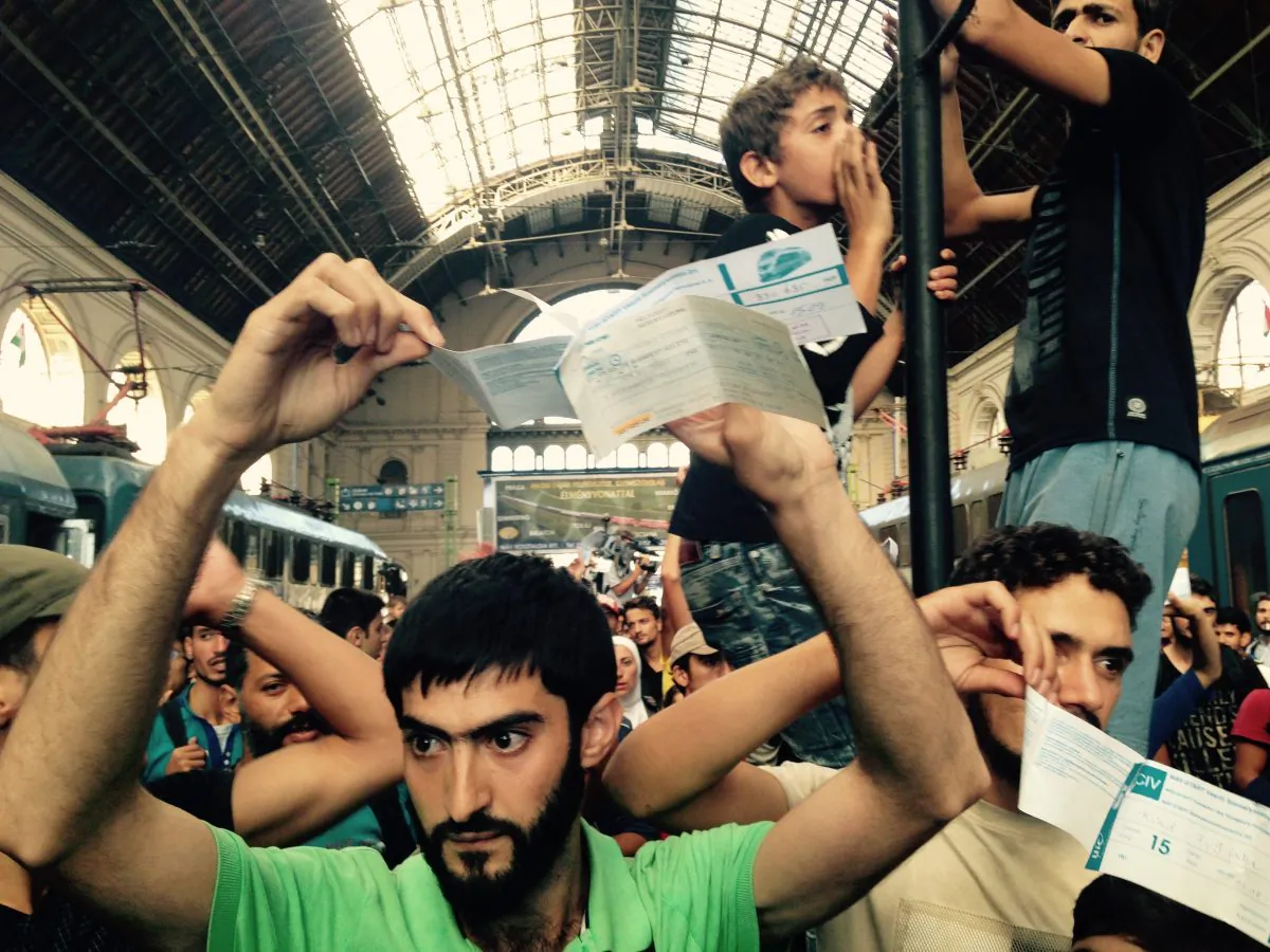 Syrian migrants show their train tickets to Germany and demand being let on the train as Keleti train terminal in Budapest, Hungary, was closed Tuesday, Sept. 1, 2015. (AP Photo/Pablo Gorondi)