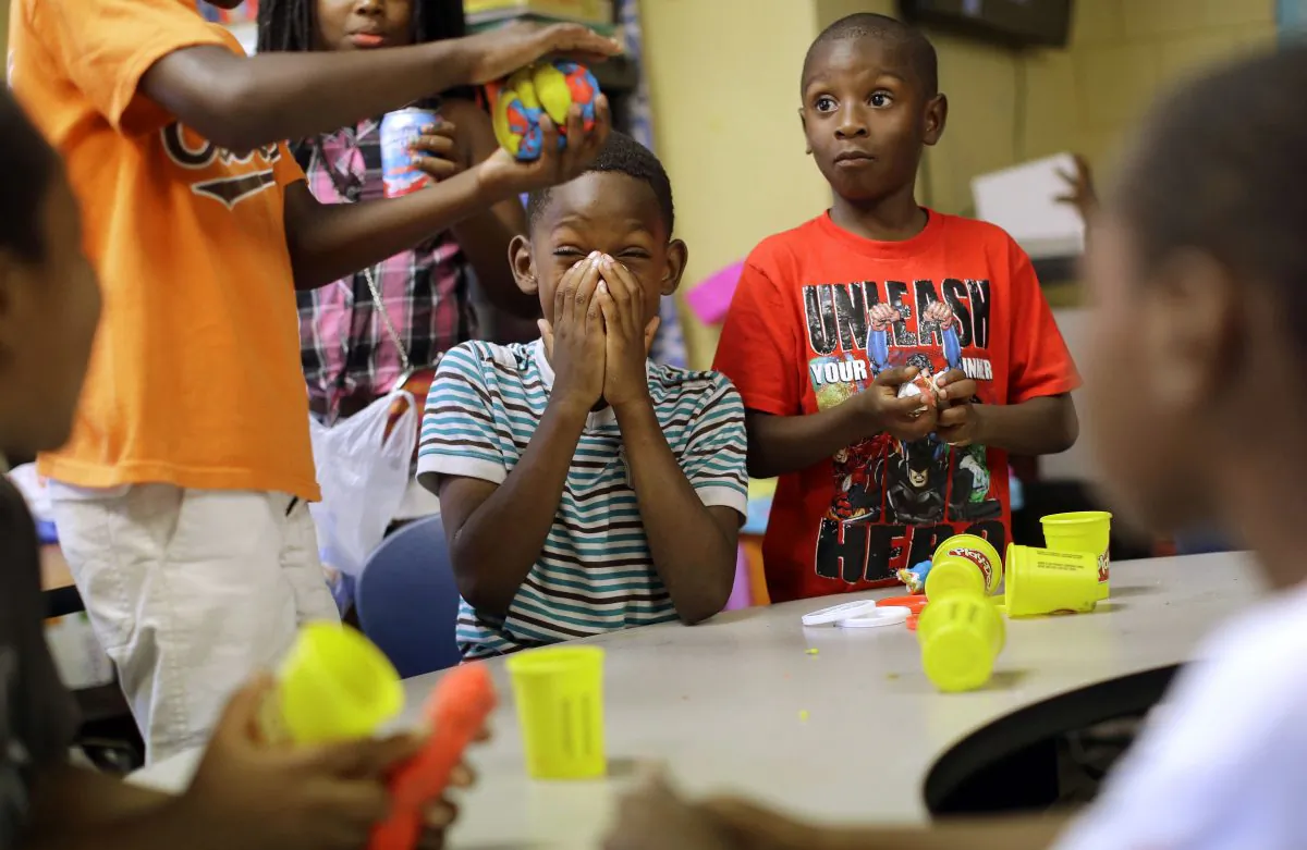 In this Aug. 19, 2015, photo, children play with Play-Doh at Kids Safe Zone community center in Baltimore. The clubhouse, which occupies an abandoned laundromat, opened in June in response to unrest that ripped through the neighborhood's streets and marked the beginning of the most violent summer the city has seen in more than four decades. (AP Photo/Patrick Semansky)