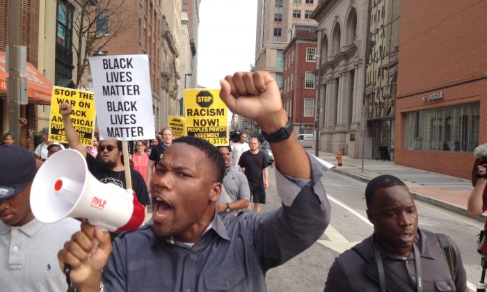 Pastor Westley West, from Faith Empowered Ministries, leads protesters as they march towards Pratt Street and the Inner Harbor, Wednesday, Sept. 2, 2015, in Baltimore, as the first court hearing was set to begin in the case of six police officers criminally charged in the death of Freddie Gray. (Lloyd Fox/The Baltimore Sun via AP) 