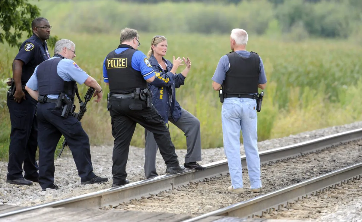 Police officers confer while searching for suspects in the shooting of a police officer Tuesday, Sept. 1, 2015  outside Fox Lake, Ill. (AP Photo/Michael Schmidt)