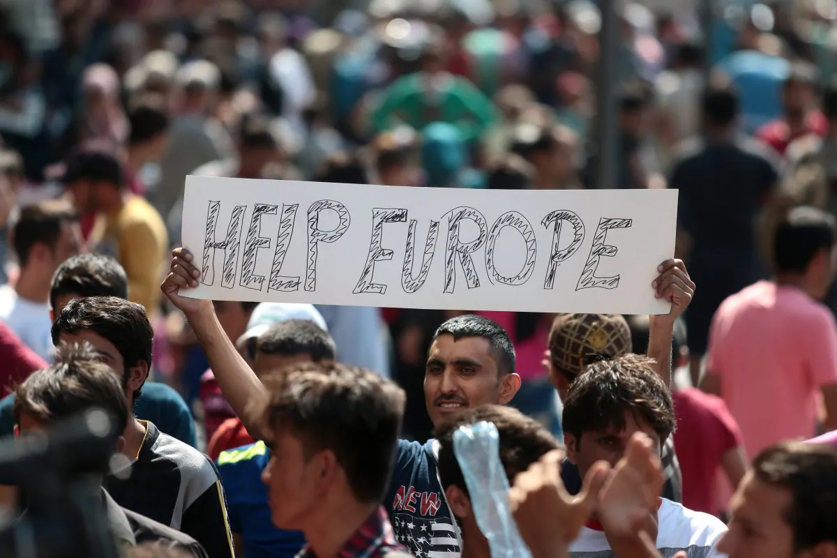 A man hold a placard reading "Help Europe" as Syrian and Afgan refugees attend a protest rally to demand to travel to Germany, outside the Keleti (East) railway station in Budapest, on Sept. 2, 2015. (Ferenc Isza/AFP/Getty Images)