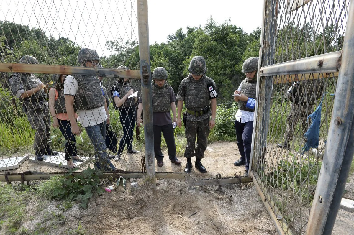 In this Aug. 9, 2015 file photo provided by the Defense Ministry, an unidentified South Korean army official, second from right, gives a briefing to the media at the scene of a blast inside the demilitarized zone in Paju, South Korea. (The Defense Ministry via AP)