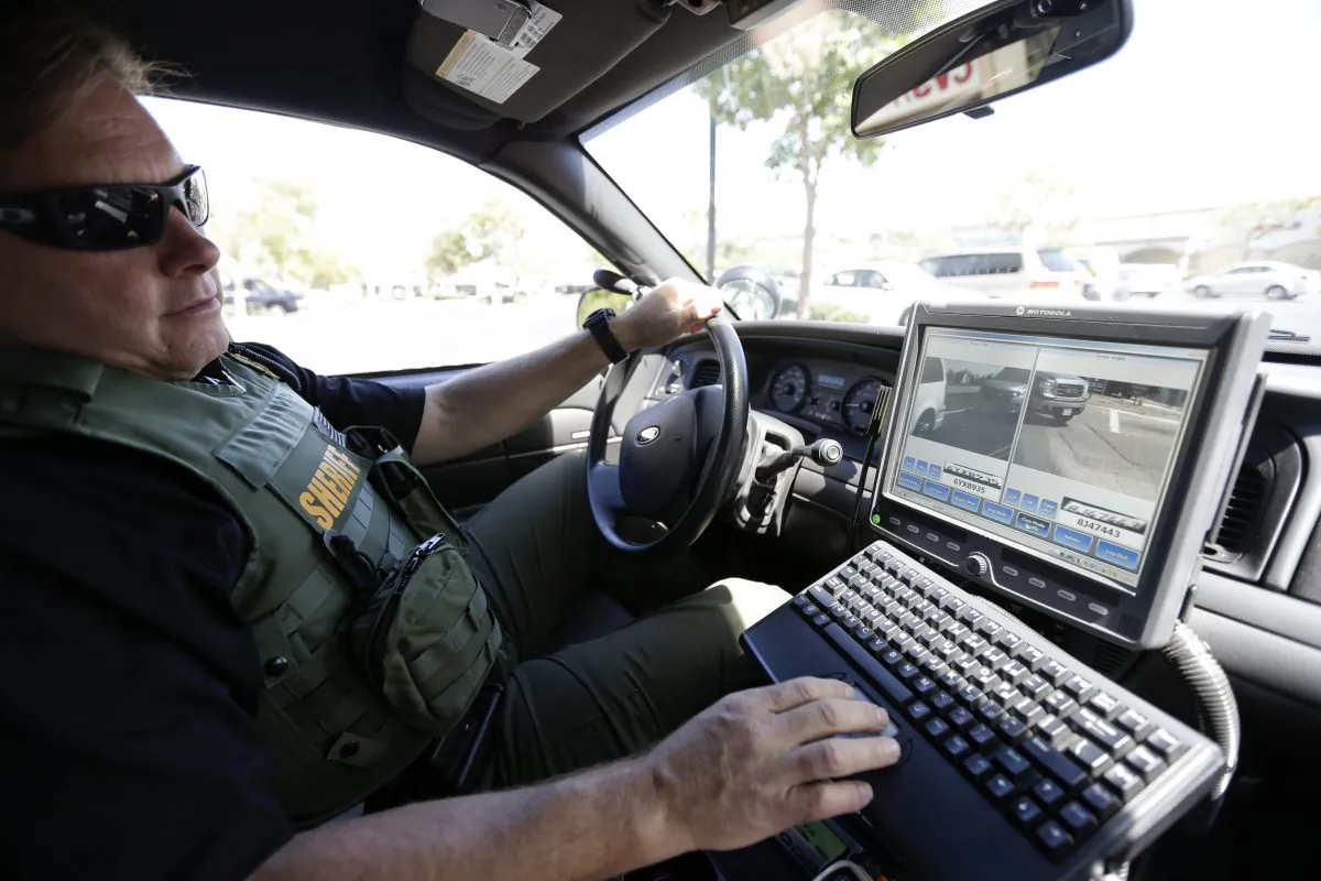 In this file photo, a San Diego County Deputy Sheriff looks at a monitor as his vehicle reads the license plates of cars in a parking lot in San Marcos, Calif., on Sept. 17, 2014. (Gregory Bull/AP Photo)