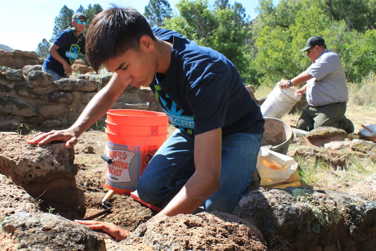 This Tuesday, July 21, 2015 photo Vidal Gonzales, center, of Santa Clara Pueblo applies mortar while reconstructing one of the walls at Tyuonyi Pueblo at Bandelier National Monument near Los Alamos, N.M. (AP Photo/Susan Montoya Bryan)