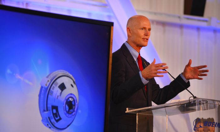 Gov. Rick Scott speaks during the grand opening for Boeing's Commercial Crew and Cargo Processing Facility (C3PF) at Kennedy Space Center, Fla. on Friday, Sept. 4, 2015. On the screen at left is a rendering of the CST-100 Starliner. The building was formerly a processing facility for the space shuttle. (Malcolm Denenark/Florida Today via AP)