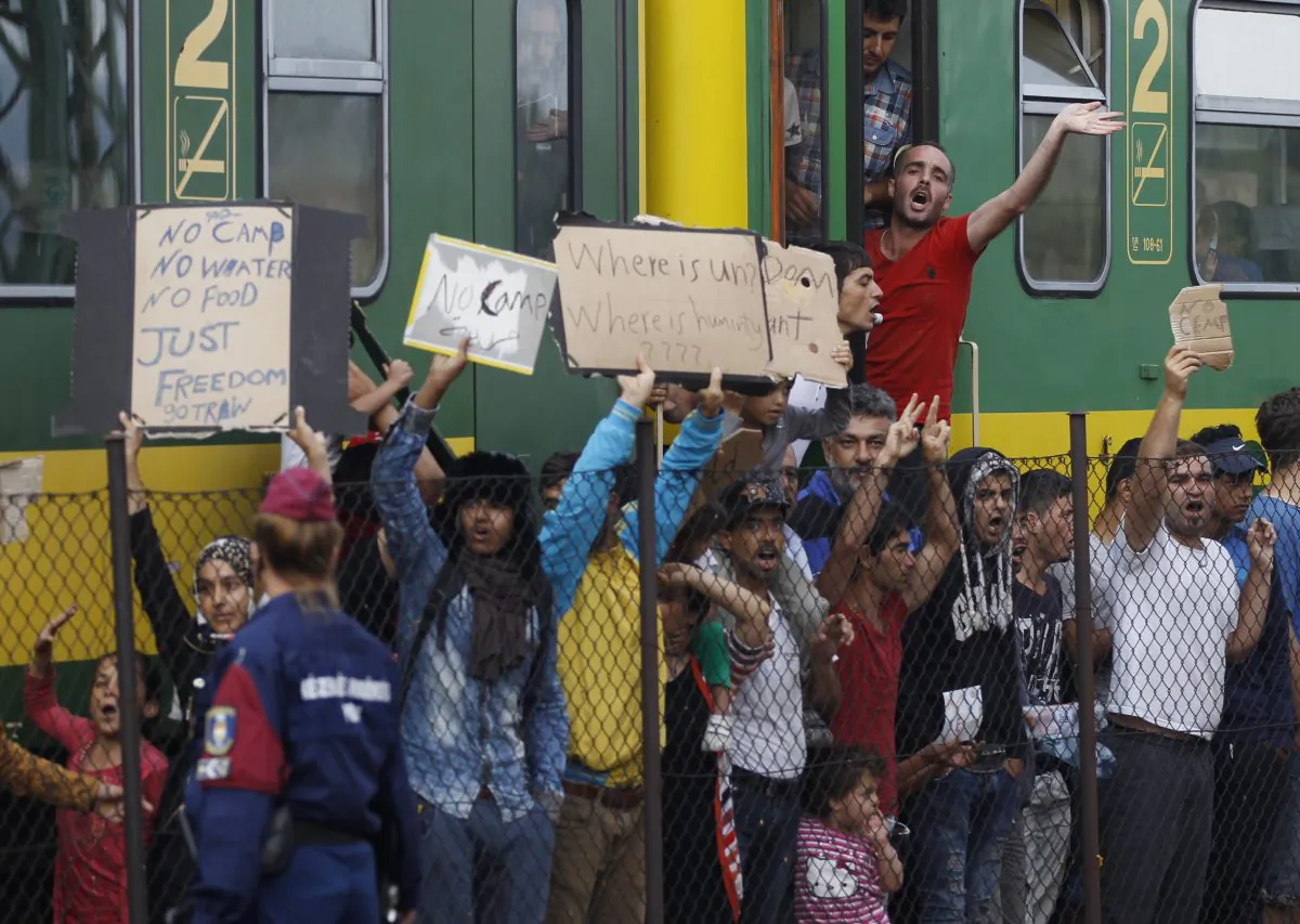 People shout slogans outside a train that was stopped in Bicske, Hungary, Friday, Sept. 4, 2015. (AP Photo/Petr David Josek)