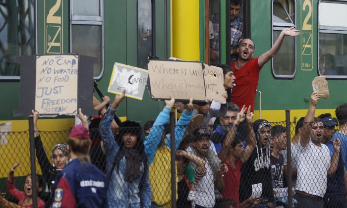 People shout slogans outside a train that was stopped in Bicske, Hungary, Friday, Sept. 4, 2015. (AP Photo/Petr David Josek)
