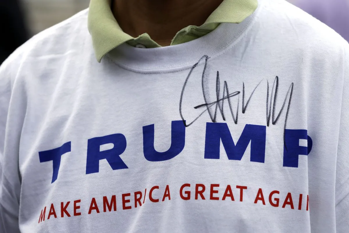 In this Aug. 29, 2015, file photo, Donald Trump supporter John Wang wears a shirt autographed by the Republican presidential candidate outside the National Federation of Republican Assemblies in Nashville, Tenn. (AP Photo/Mark Humphrey)
