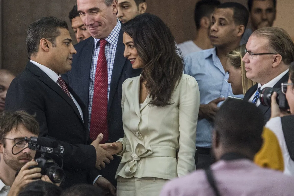 Canadian Al-Jazeera journalist Mohamed Fahmy (L) shakes hands with Amal Clooney (C), the human rights lawyer representing him, before the start of his trial along with Egyptian Baher Mohamed (unseen), both accused of supporting the blacklisted Muslim Brotherhood in their coverage for the Qatari-owned broadcaster, on August 29, 2015, in the capital Cairo. (Khaled Desouki/AFP/Getty Images)