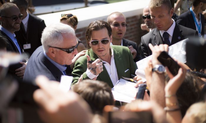 Johnny Depp signs autographs for fans as he departs after the photo call for the film Black Mass during the 72nd edition of the Venice Film Festival in Venice, Italy, Friday, Sept. 4, 2015.  (Photo by Joel Ryan/Invision/AP)