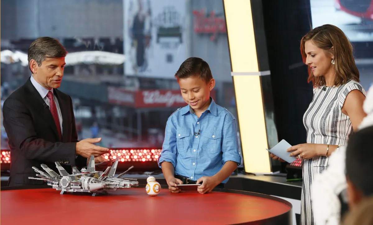 Co-anchors, George Stephanopoulos, left, and Paula Faris, right, look on as EvanTubeHD, a digital star from the Maker Studios network, unboxes the LEGO Star Wars Millennium Falcon and the Star Wars BB-8 App Enabled Droid from Sphero, on "Good Morning America" in New York, Sept. 3, 2015, as part of the epic global event marking the countdown to "Force Friday" when merchandise from Star Wars: The Force Awakens goes on sale. (Photo by Stuart Ramson/Invision for Disney Consumer Products/AP Images)
