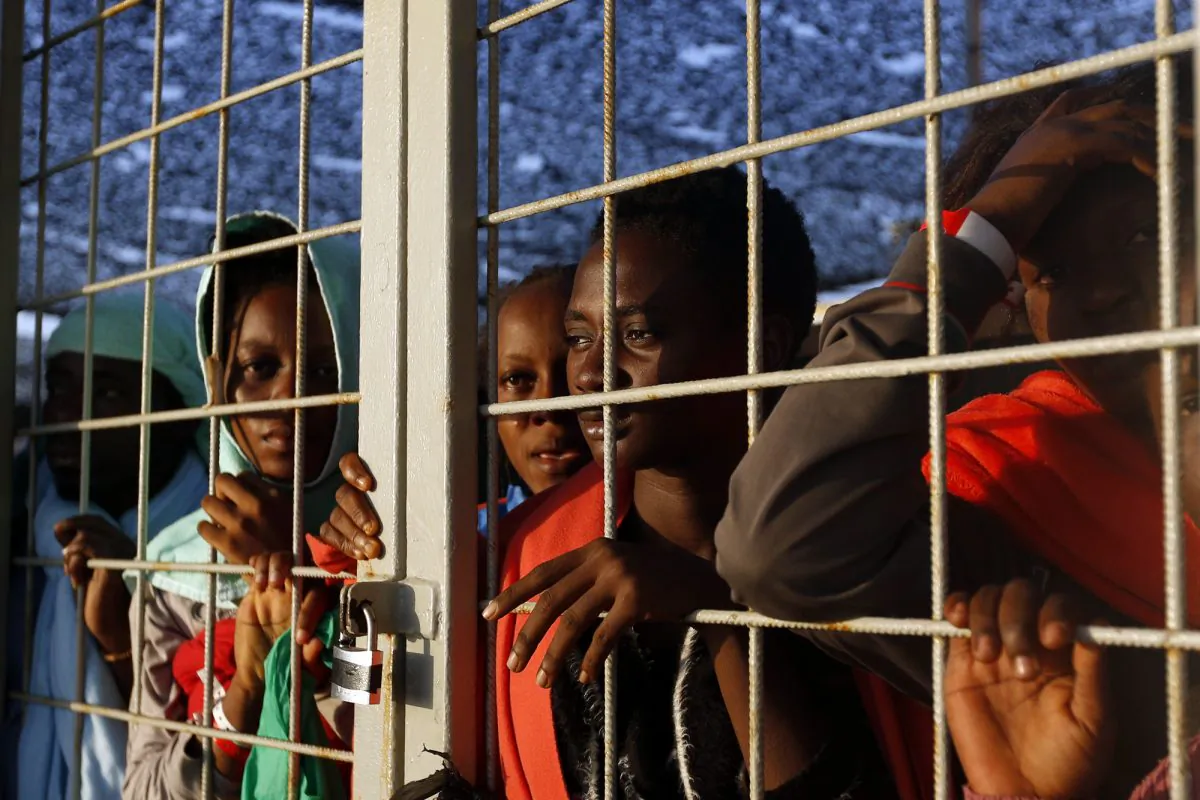 FILE - In this Thursday, Sept. 3, 2015 file photo, migrants rescued off the Libyan coast peer out a gate on the Siem Pilot Norwegian ship to get the first sight of the island of Sardinia as they sail in the Mediterranean sea towards the Italian port of Cagliari. As of September 2015, more than 2,800 migrants have died trying to reach Europe, mostly at sea, according to the International Organization for Migration. (AP Photo/Gregorio Borgia, File)