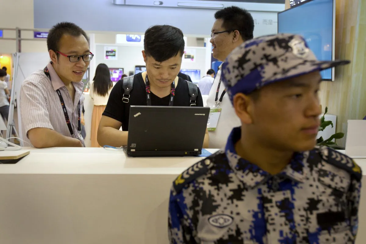 Visitors use a laptop computer at a display booth as a security guard stands nearby at the Global Mobile Internet Conference in Beijing April 29, 2015. (AP Photo/Mark Schiefelbein)