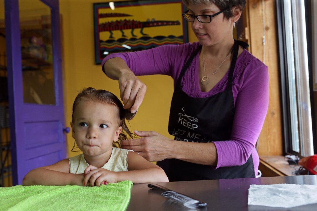 In a Friday, Aug. 28, 2015 photo, Charlotte Moore, 2, of Crestwood, receives a head lice screening from store owner and technician, Libby Lutz, at Lice Busters, a professional head lice removal company, in Richmond Heights, Mo.  A new strain of lice resistant to most treatment is causing worries as kids return to school, a time when outbreaks can occur and prove uncomfortable, and shame-inducing. (Cristina M. Fletes/St. Louis Post-Dispatch via AP)  EDWARDSVILLE INTELLIGENCER OUT; THE ALTON TELEGRAPH OUT; MANDATORY CREDIT