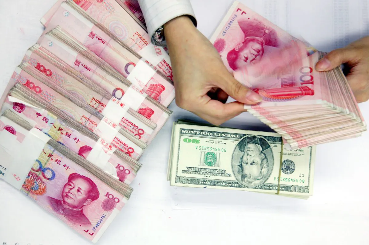 A clerk counts stacks of Chinese yuan and U.S. dollars at a bank in Shanghai, China. (China Photos/Getty Images)