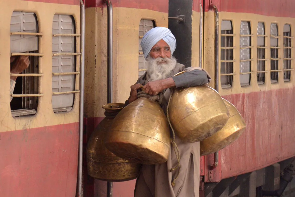 An Indian milkman carries milk containers as he boards a train at a railway station in Amritsar on Feb. 26, 2015. (Narinder Nanu/AFP/Getty Images)