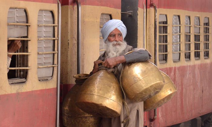 An Indian milkman carries milk containers as he boards a train at a railway station in Amritsar on February 26, 2015. (Narinder Nanu/AFP/Getty Images)