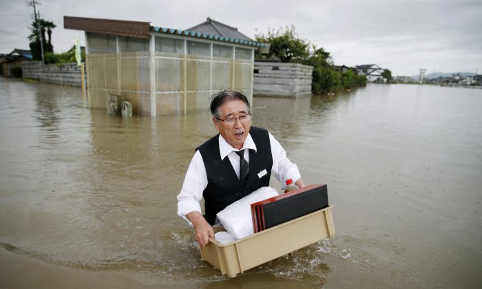 A man carries belongings through a flooded street in Oyama, Tochigi prefecture, northeast of Tokyo Thursday, Sept. 10, 2015. (Kyodo News via AP) 