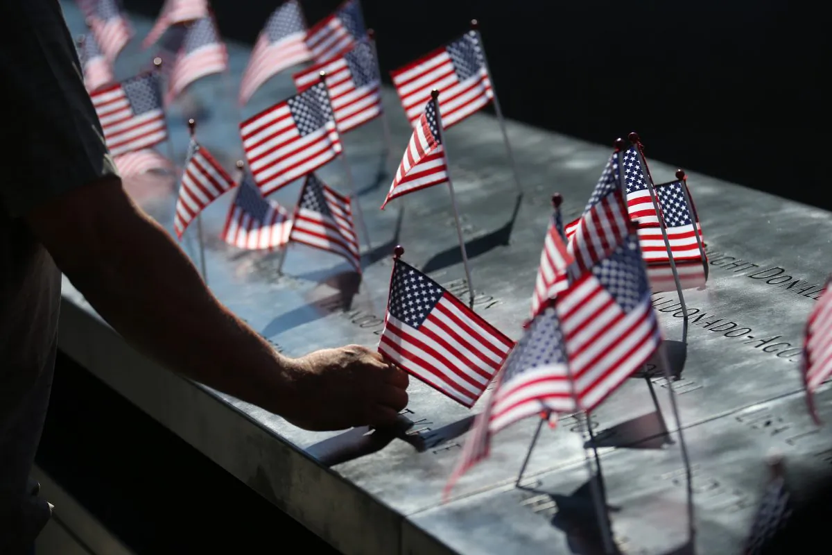 A man fixes an American flag that had fallen during memorial ceremonies for the eleventh anniversary of the terrorist attacks on lower Manhattan at the World Trade Center site in New York City, on Sept. 11, 2012. (Chang W. Lee/Getty Images)