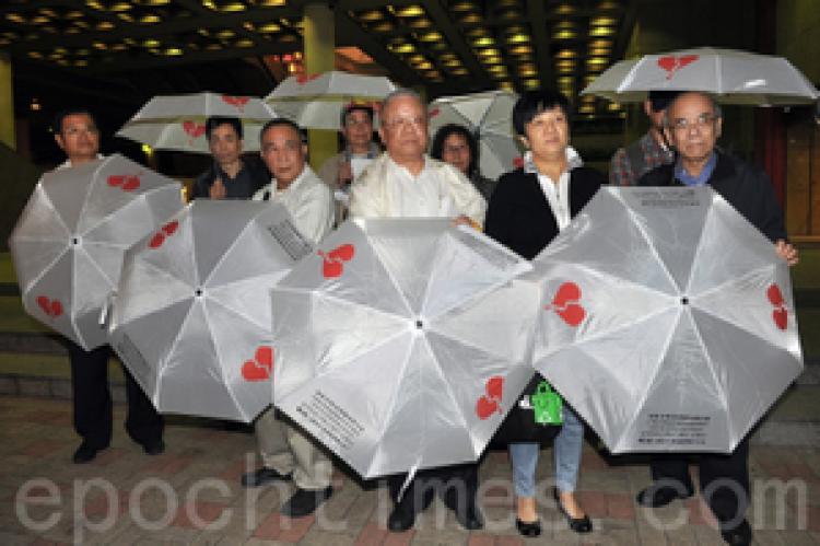 Nine members of the Hong Kong (China) Investment Rights Concern Group each carrying an umbrella with symbol and info of the group. (Kwong Tianming/Epoch Times) Nine members of the Hong Kong (China) Investment Rights Concern Group each carrying an umbrella with symbol and info of the group. (Kwong Tianming/Epoch Times)