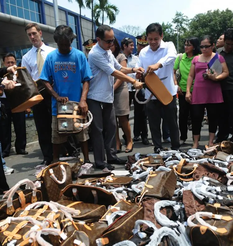 Workers prepare to destroy fake handbags in a a ceremonial destruction of counterfeit and pirated goods at the National Police headquarters in Manila, Philippines, on June 23.