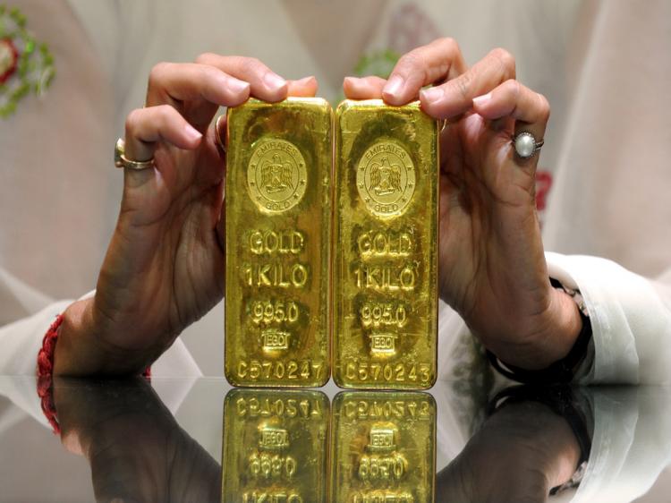 TARNISHED? An Indian saleswoman holds two bars of 24 carat gold, weighing a kilogram each, at Forever Precious Jewellery and Diamonds Ltd. in Ahmedabad on May 14, 2010. Prices for gold have come down in recent weeks as more investors are putting money into stocks.(Sam Panthaky/AFP/Getty Images)