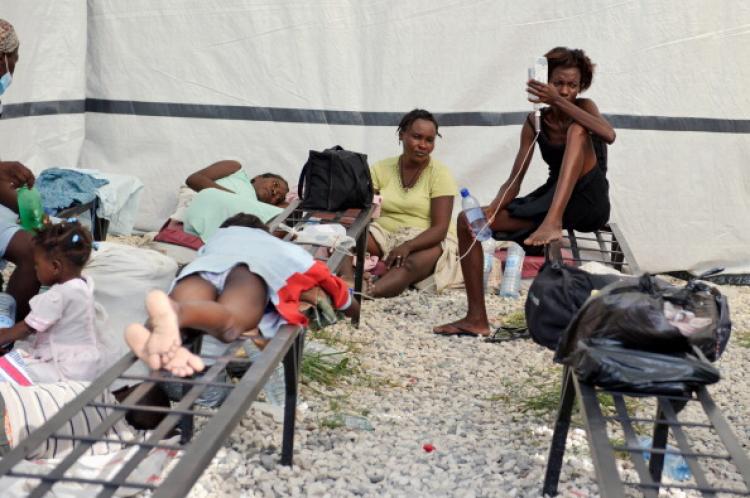 A mother holds the IV of her child in a triage medical tent setup, outside St. Nicolas Hospital after a cholera outbreak has hit the rural countryside Oct. 22, 2010 in St. Marc, Haiti. (Frederic Dupoux/Getty Images)