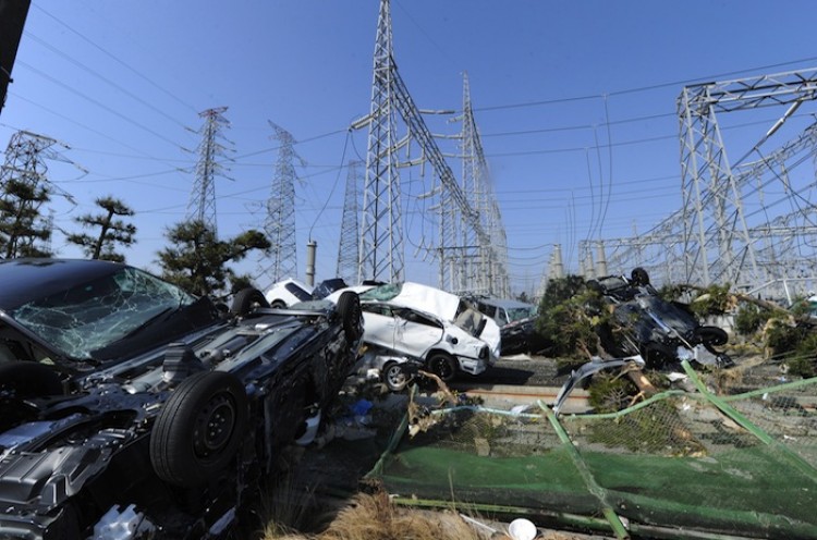 CRIPPLED: Cars smashed by the tsunami sit piled together next to a power grid to the east of Sendai, Japan on March 13, two days after the massive magnitude 9.0 earthquake and tsunami hit the region and crippled the nation's power supply.  (Mike Clarke/Getty Images)