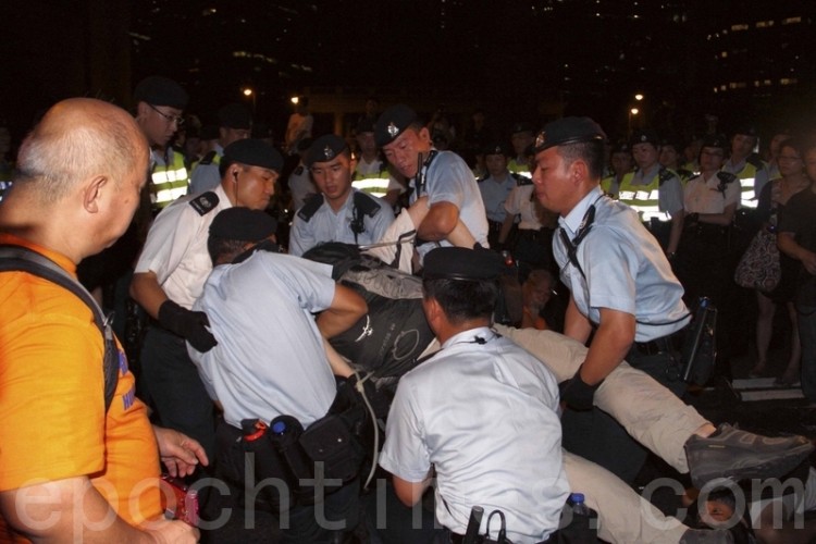 Police carry away a demonstrator after the July 1, 2011 protest march in Hong Kong. (Cai Wenwen/The Epoch Times) Police carry away a demonstrator after the July 1, 2011 protest march in Hong Kong. (Cai Wenwen/The Epoch Times)
