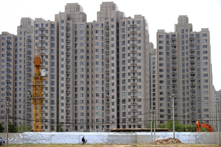 A man on a bicycle is riding past a real-estate development in Beijing. (Getty Images) A man on a bicycle is riding past a real-estate development in Beijing. (Getty Images)