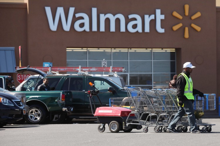 A man pushes carriages outside of a Walmart store A man pushes carriages outside of a Walmart store