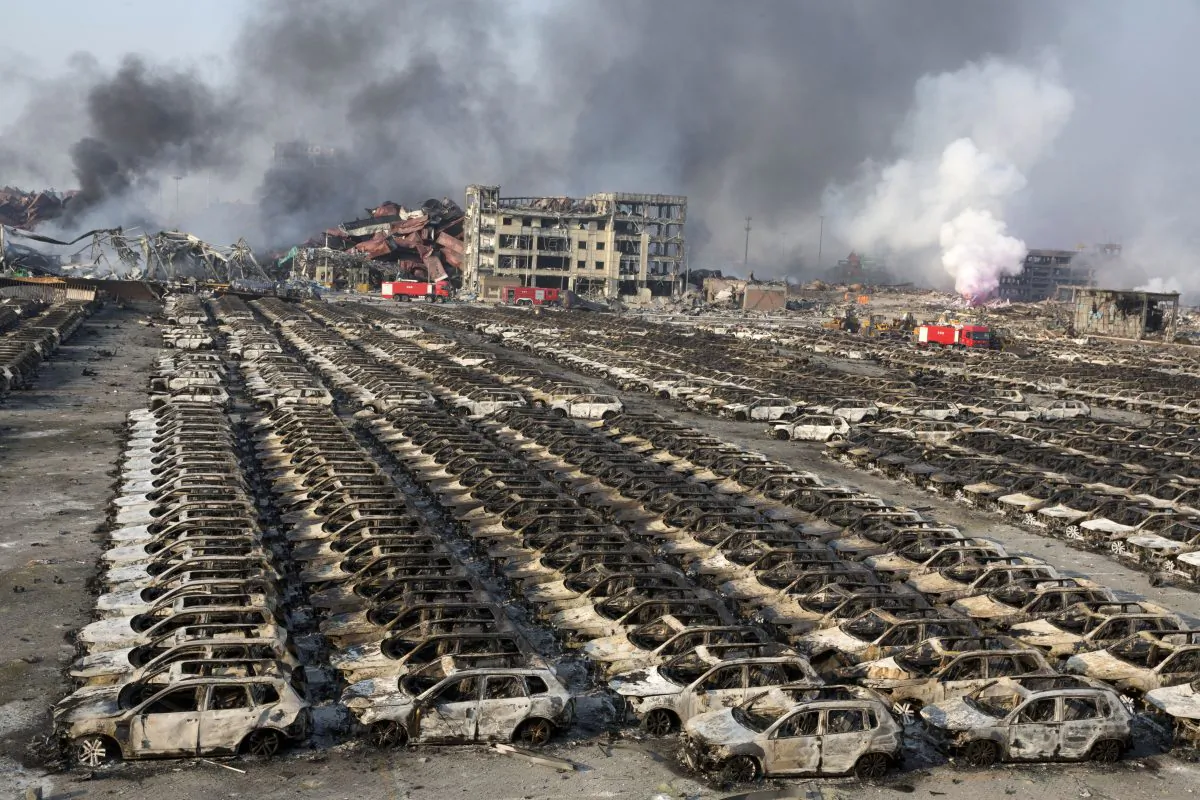 Smoke billows from the site of an explosion that reduced a parking lot filled with new cars to charred remains at a warehouse in northeastern China's Tianjin municipality on Aug. 13, 2015. (AP Photo/Ng Han Guan)