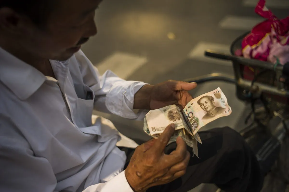 A man checks Chinese yuan bills in Beijing on July 28, 2015. (Fred Dufour/AFP/Getty Images)
