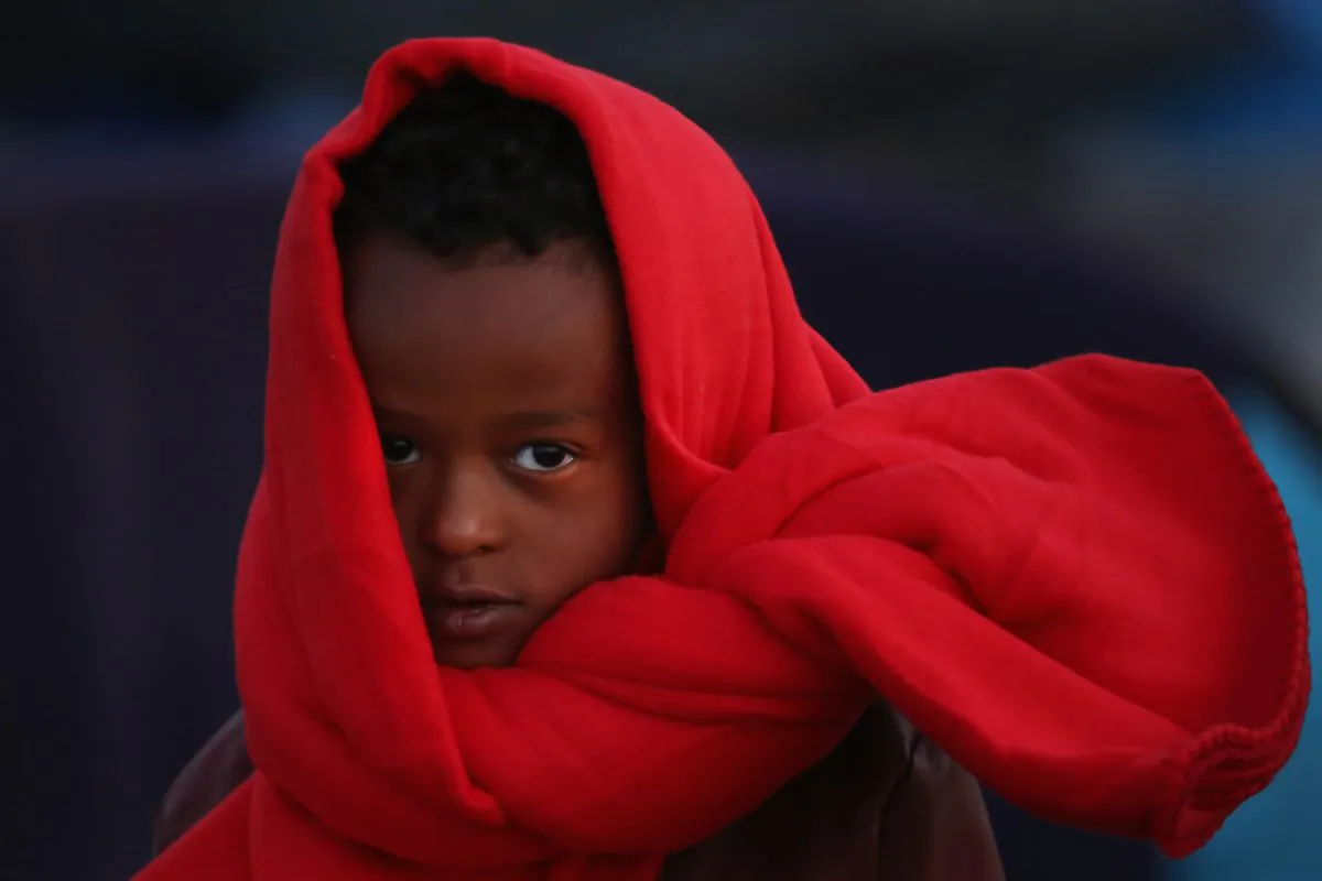 A young boy wraps up to keep warm as migrants wake up to a cold morning at the Hungarian border with Serbia in Roszke, Hungary, on Sept. 13, 2015. A record number of 4,000 people crossed the Hungarian border with Serbia on Sept. 12. (Christopher Furlong/Getty Images)