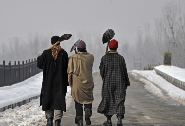 Kashmiri municipal workers walk on the b