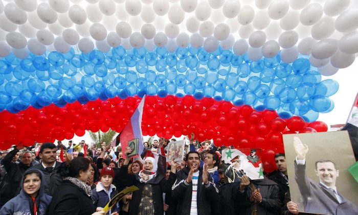 FILE - In this Feb. 7, 2012, file photo, pro-Syrian government protesters gather under a large Russian flag made with balloons as they cheer a convoy believed to be transporting Russian Foreign Minister Sergey Lavrov in Damascus, Syria. In ramping up its military involvement in Syria's civil war, Russia appears to be betting that the West, horrified by Islamic State's atrocities, may be willing to tolerate Syrian President Bashar Assad for a while, perhaps as part of a transition. (AP Photo/Muzaffar Salman, File)