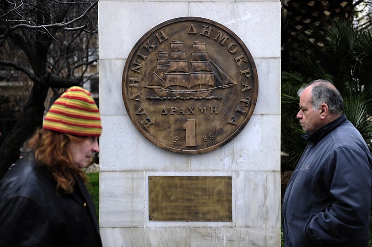 People walk past a monument featuring a replica of the last edition of the Greek currency, the drachma People walk past a monument featuring a replica of the last edition of the Greek currency, the drachma