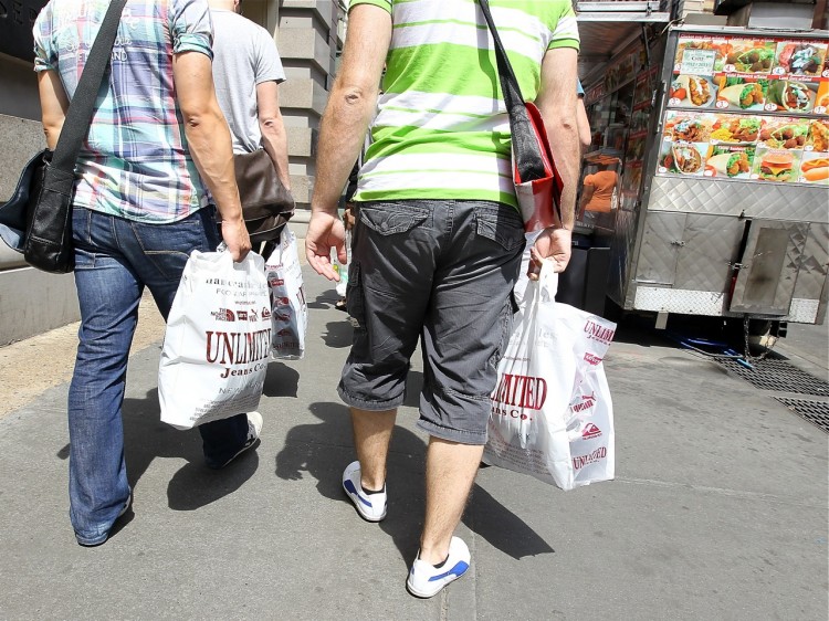 142977122 Pedestrians carry shopping bags