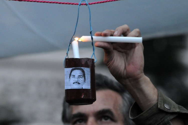 A man lights a candle during a vigil in Epoch Times Photo