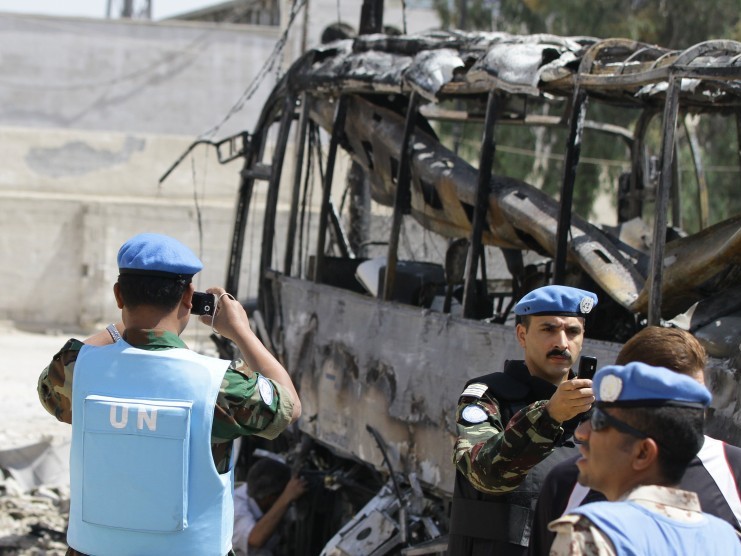 UN observers photograph the scene by a bombed bus outside a Shiite holy shrine in the Sayyida Zeinab suburb of Damascus on June 14, 2012. (LouaiBesgara/AFP/GettyImages)
