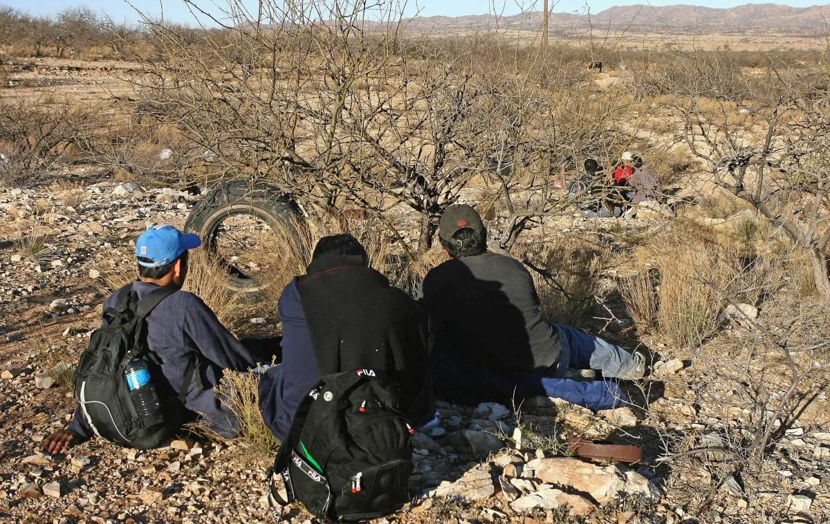 Mexican immigrants take a rest behind bushes in the Arizona Desert near Sasabe, Sonora State, during an attempt to illegally cross the U.S.-Mexico border, on April 6, 2006. (Omar Torres/AFP/Getty Images)